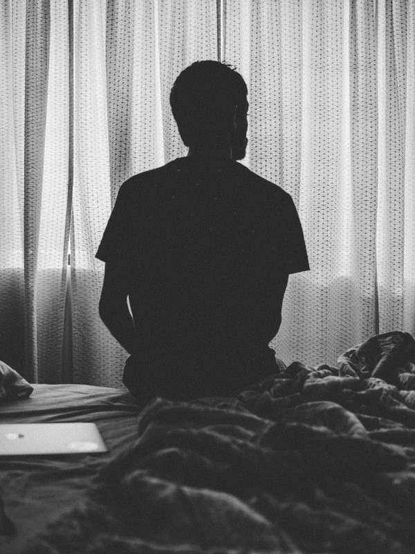 Man sitting on side of bed, indicating he is stressed